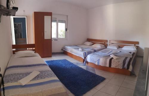 a room with three beds and a blue rug at Apartments Daris in Ulcinj