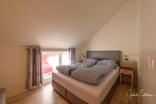 a bed in a small room with a window at Lofotveggen Panorama in Ballstad