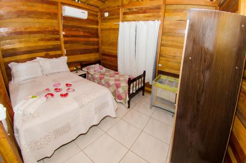 a bedroom with a bed in a wooden cabin at Chalés da Sinhá in Penha