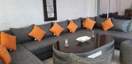 a living room with a gray couch with orange pillows at Appartement Agadir Awrir in Agadir