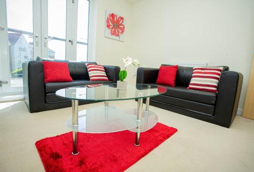 a living room with a glass table and a black couch at Lake View Apartment in Northampton