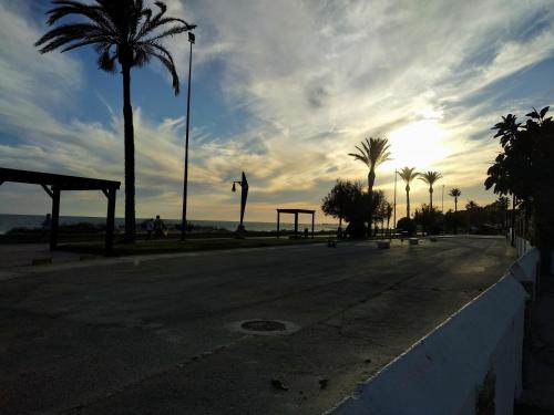 チクラナ・デ・ラ・フロンテーラにあるLa Barrosa duplexのヤシの木と夕日が沈む静かな通り