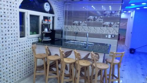 a kitchen with a bar with wooden stools at Al-Madina Tower Apartments in Marsa Matruh