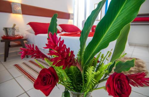 a vase filled with red flowers and red roses at Pousada Villa Del Rey POSSUIMOS GERADOR in Paraty