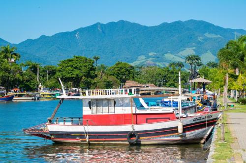 a red and white boat sitting in the water at Pousada Villa Del Rey POSSUIMOS GERADOR in Paraty