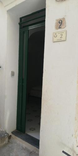 una porta verde con un cartello su un muro di Il Puntino ad Atrani