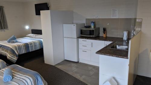 a small kitchen with a microwave and a bed at Harrington Village Motel in Harrington