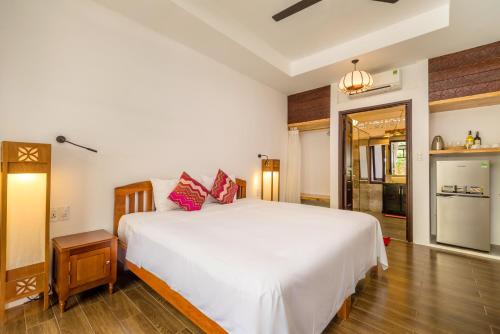 a bedroom with a large white bed with red pillows at An Bang Coco Villa in Hoi An