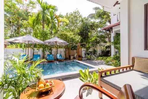 a patio with a pool and a table with a bowl of fruit at An Bang Coco Villa in Hoi An