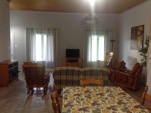 a living room with a couch and chairs and a table at Les appartement 4 saisons des iles in Saint-Gédéon