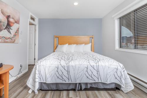 a white bedroom with a bed with white sheets and a window at Westridge Motor Inn in Osoyoos