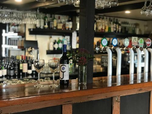 a bottle of wine sitting on a bar with wine glasses at Caledonian Inn in Robe