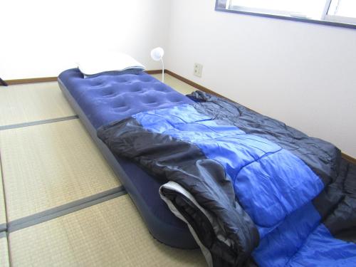 丸亀市にある丸亀 ゲストハウス ウェルかめの青い掛け布団が備わるドミトリールームのベッド1台分です。
