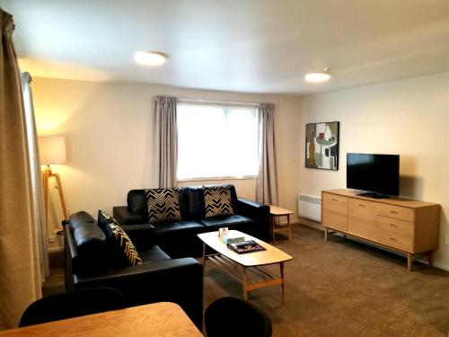 a living room with a couch and a tv at The Victoria Hotel Dunedin in Dunedin