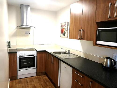 a kitchen with a sink and a stove top oven at The Victoria Hotel Dunedin in Dunedin