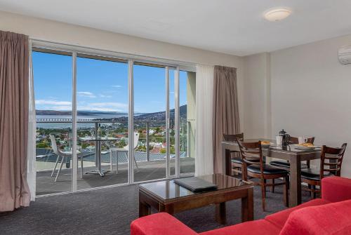 a living room with a red couch and a table and a large window at Bay View Villas in Hobart