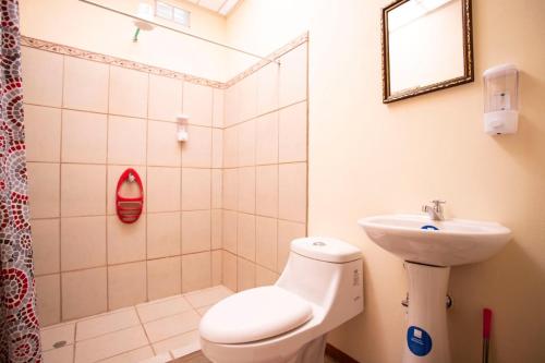 uma casa de banho com um WC, um lavatório e um chuveiro em Flor de Katty Hostel Airport em Alajuela