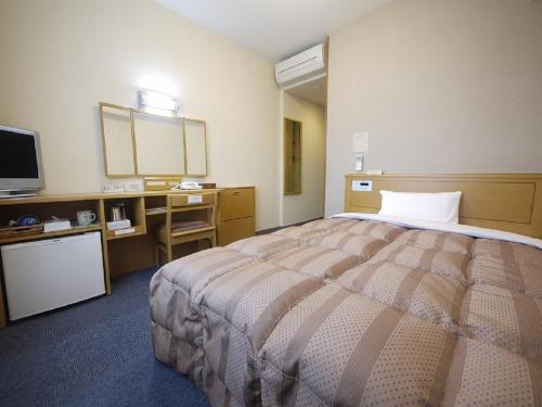 a hotel room with a bed and a television at Hotel Route-Inn Wakamiya Inter in Miyawaka