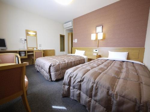 a hotel room with two beds and a desk at Hotel Route-Inn Wakamiya Inter in Miyawaka