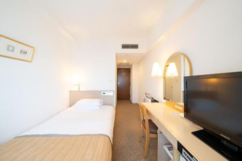 a hotel room with a bed and a flat screen tv at Hotel Terrace The Square Hitachi in Hitachi