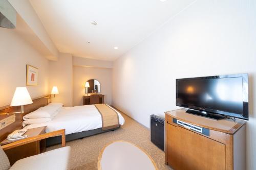 a hotel room with a bed and a flat screen tv at Hotel Terrace The Square Hitachi in Hitachi