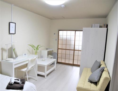 a white room with a desk and a table and a couch at Osaka U-Shuku in Osaka