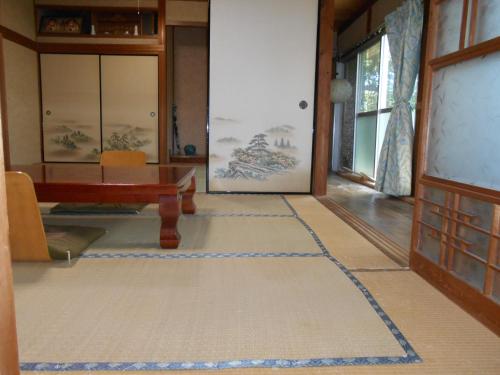 a living room with a table and a rug at ゲストハウスよろずや in Nahari