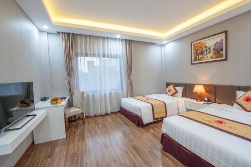 ein Hotelzimmer mit 2 Betten und einem TV in der Unterkunft Sunrise Hanoi Hotel in Hanoi