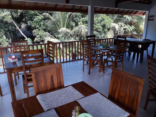 um restaurante com mesas e cadeiras de madeira e uma varanda em Serah's Homestay em Kuta