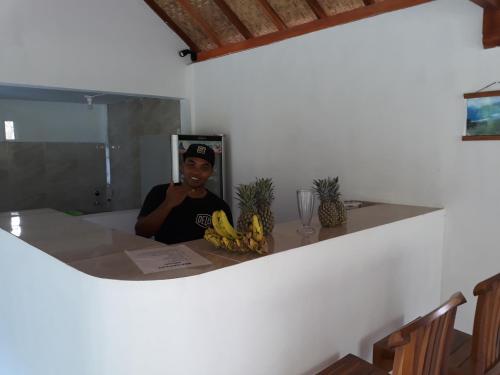 a woman sitting at a table with a bunch of bananas at Serah's Homestay in Kuta Lombok