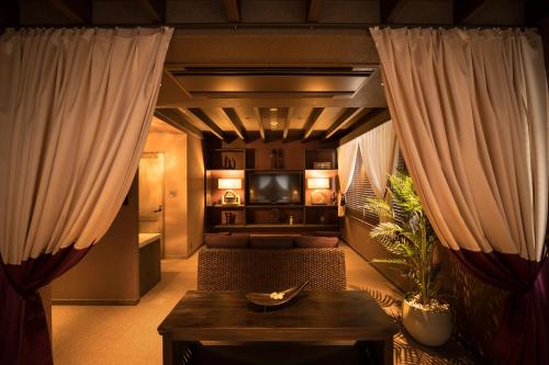HOTEL SHIKISAI KYOTO في كيوتو: غرفة معيشة مع ستائر وأريكة وطاولة