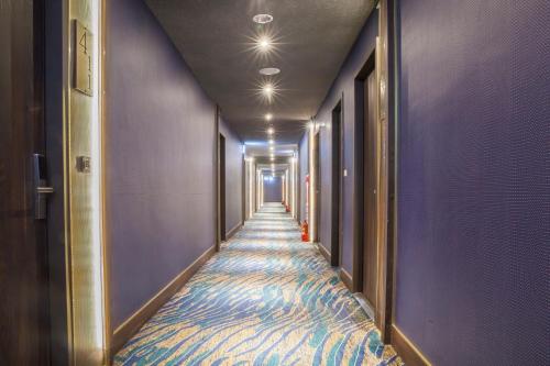 a long hallway with purple walls and a blue carpet at Saint Art Hotel in Beigang