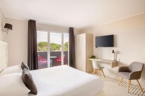 a hotel room with a bed and a desk and a window at Best Western Plus Antibes Riviera in Antibes