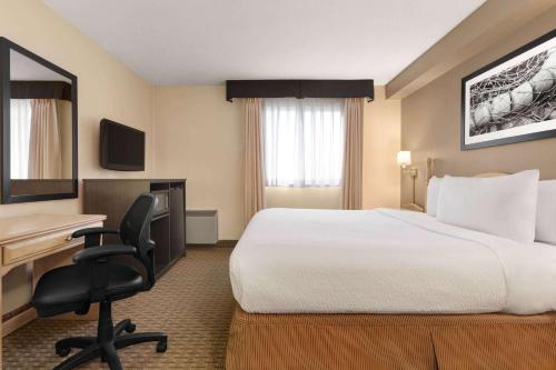 a hotel room with a bed and a desk at Travelodge Suites by Wyndham Moncton in Moncton