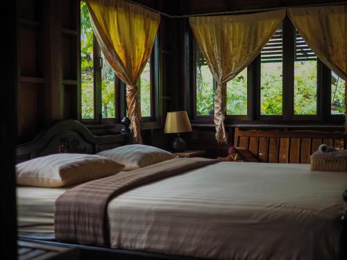 a bedroom with two beds and two windows at Baan Kong Homestay in Phra Nakhon Si Ayutthaya
