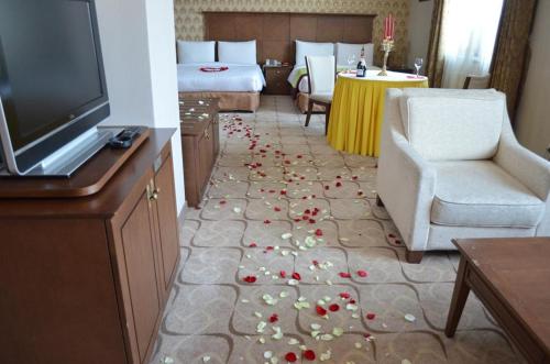 a room with a bed and a television and flowers on the floor at Sunjin Grand Hotel in Ulaanbaatar