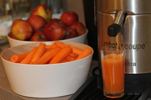 a bowl of carrots and a glass of orange juice and apples at Hotel die Hindenburg in Saalfelden am Steinernen Meer