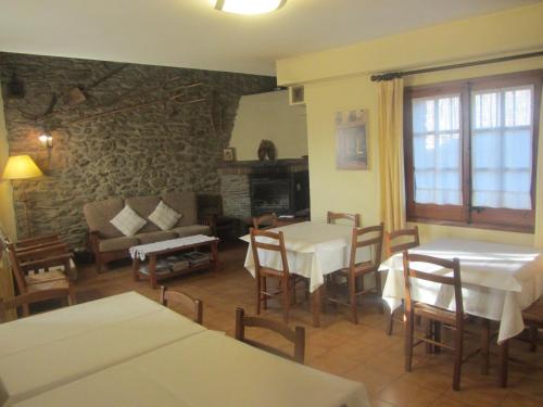 a living room with tables and chairs and a stone wall at Cal Mateu in Urtx