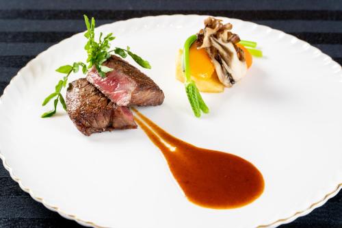 a plate of food with meat and sauce on it at Hotel Terrace The Square Hitachi in Hitachi