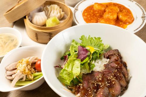 a table topped with plates of food with meat and salad at Hotel Terrace The Square Hitachi in Hitachi