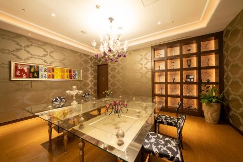 a dining room with a glass table and a chandelier at Hotel Terrace The Square Hitachi in Hitachi