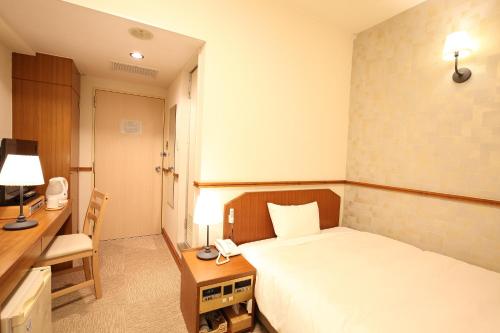 a bedroom with a bed and a desk and a telephone at Hotel Nature Nagoya Sakae Kishu Railway Group in Nagoya