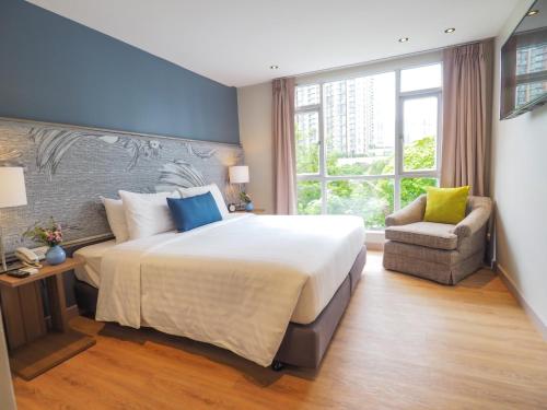 a bedroom with a large bed and a chair at Asoke Residence Sukhumvit by UHG in Bangkok