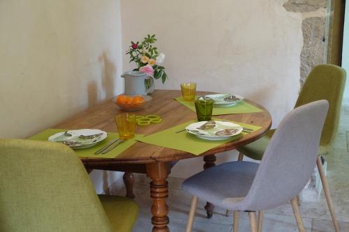 une table en bois avec des chaises et une table avec des assiettes et des verres dans l'établissement Gîte des quatre chemins, à La Vineuse