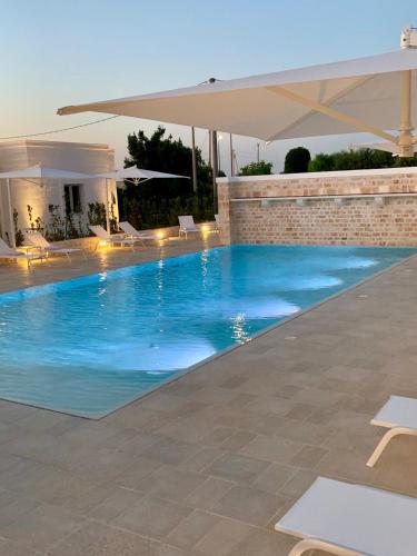 a swimming pool in a villa with an umbrella at Borgo Cozzana in Monopoli