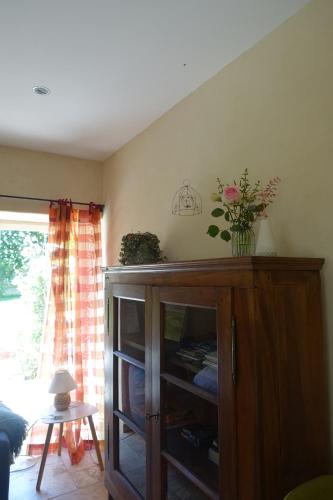 a room with a wooden cabinet with a vase of flowers on it at Gîte des quatre chemins in La Vineuse