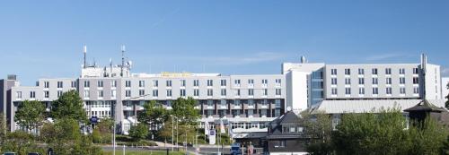 a large white building with trees in front of it at Dorint Am Nürburgring Hocheifel in Nürburg