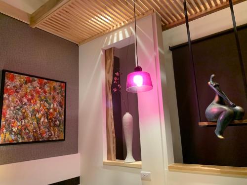 a room with a pink lamp and a painting and a statue at Roppongi Motel - JianHua in Pingtung City