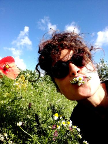 a woman wearing sunglasses eating flowers in a field at Litto Appartamenti in Tropea