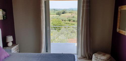 a bedroom with a bed and a large window with a view at Villa Fotini I in Amalias